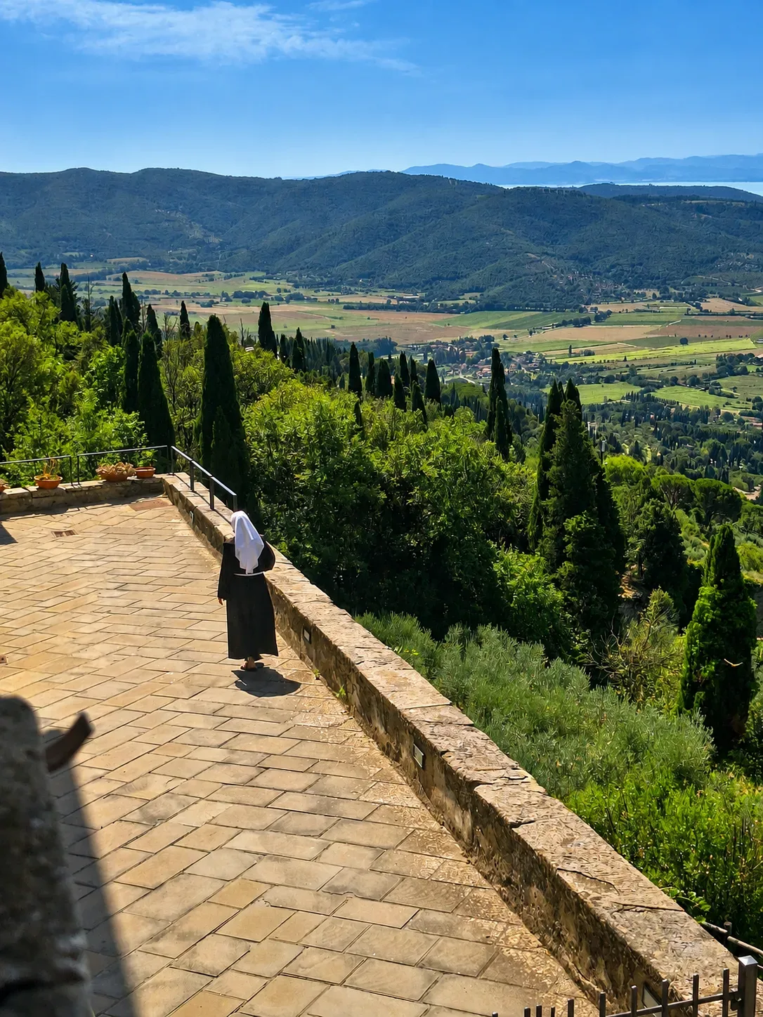 La Val di Chiana al pomeriggio vista da una finestra del Monastero di Santa Margherita, con una suora della congregazione che osserva la valle