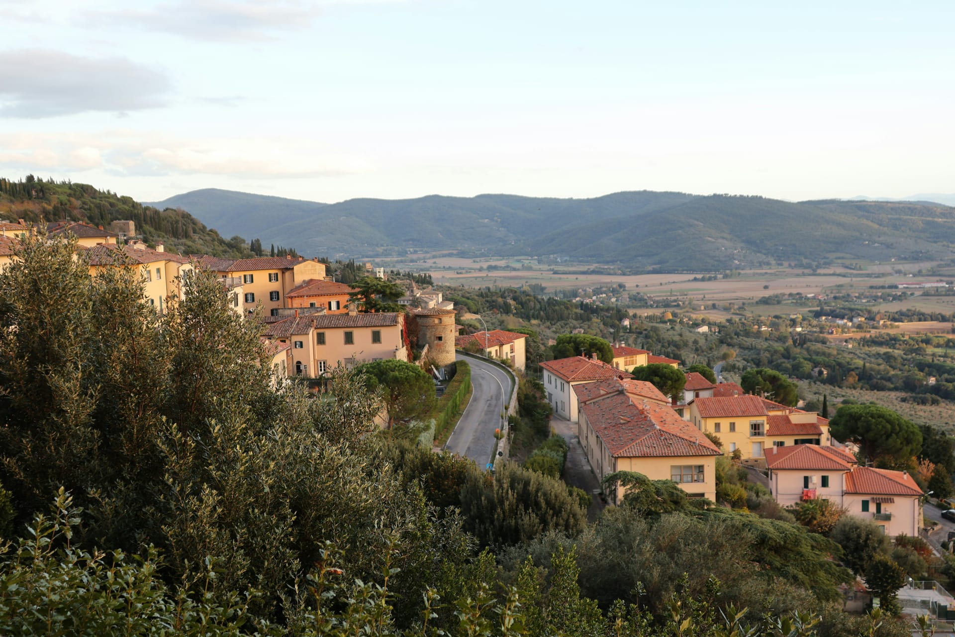 Cortona sulla collina con la Valdichiana sullo sfondo nella luce del tardo pomeriggio