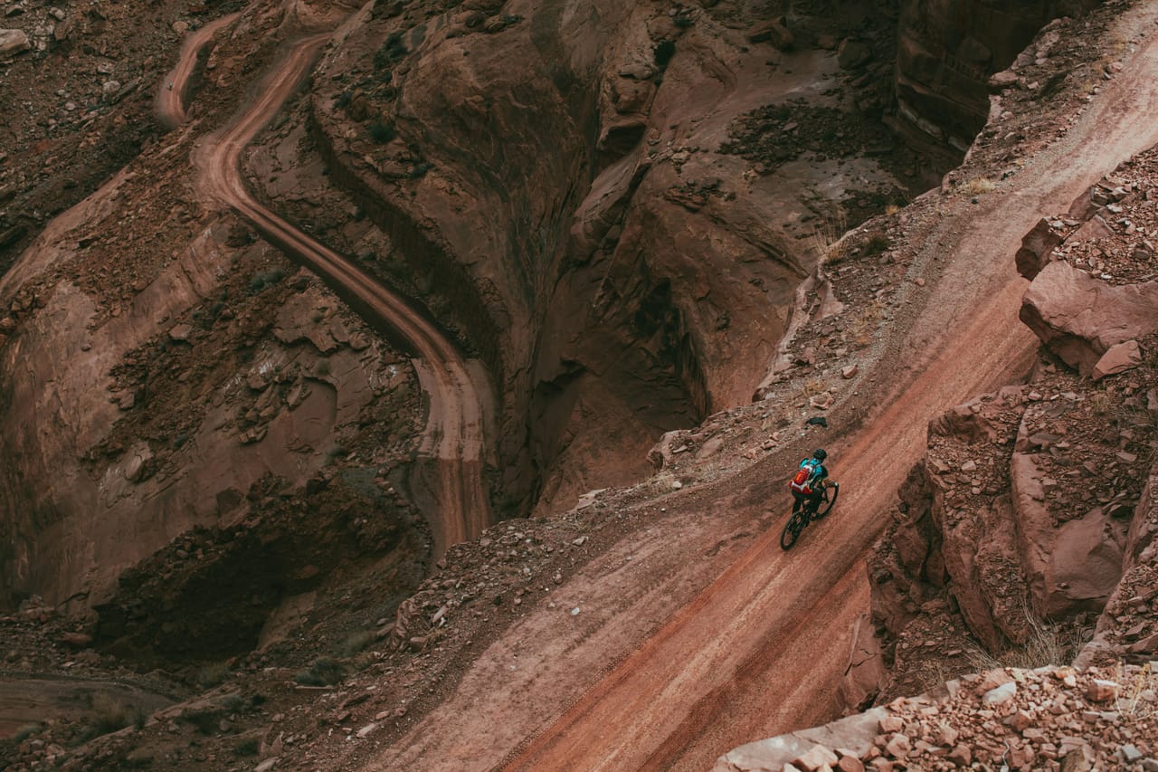 Ciclista che scende su uno sterrato verso la piana e il canale